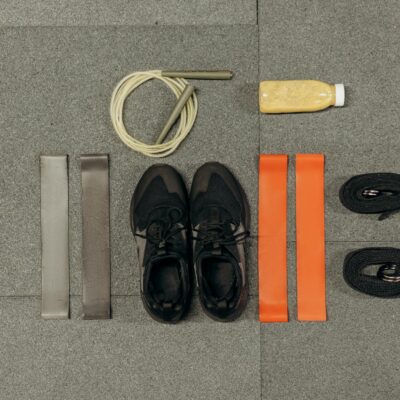 A neatly arranged flatlay featuring fitness equipment and a healthy drink on a gray surface.