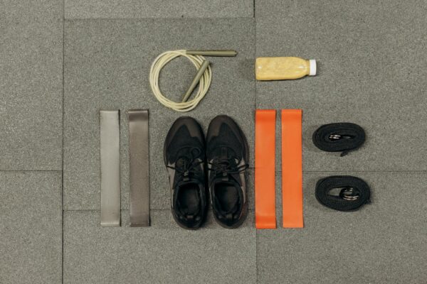 A neatly arranged flatlay featuring fitness equipment and a healthy drink on a gray surface.