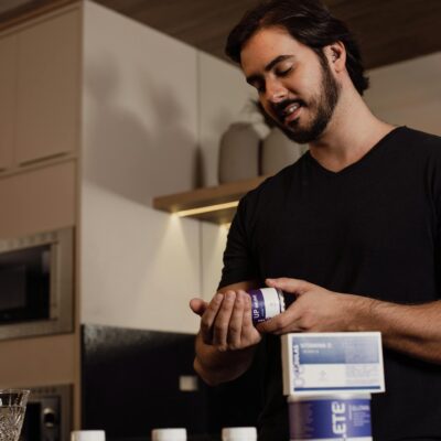 Adult man examining a supplement bottle in a modern kitchen setting, adding a touch of lifestyle and health.