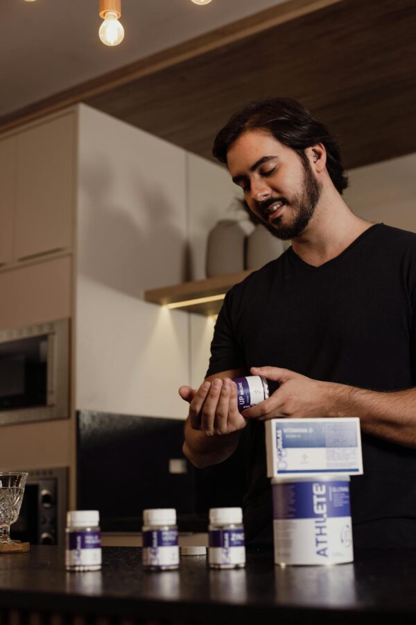 Adult man examining a supplement bottle in a modern kitchen setting, adding a touch of lifestyle and health.