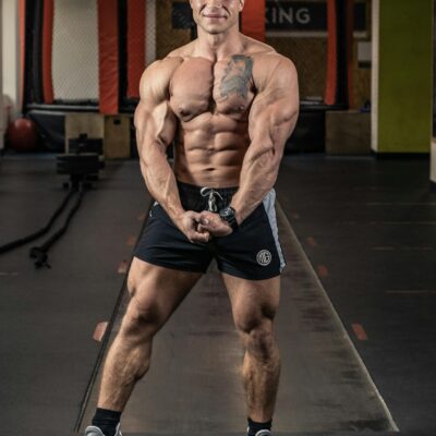 Fit man showcasing muscles in an indoor gym environment.