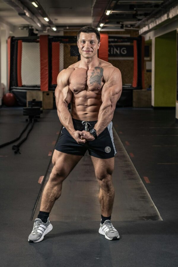 Fit man showcasing muscles in an indoor gym environment.