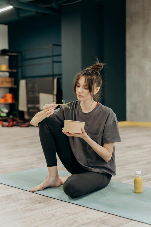 Young woman eating a healthy meal after a yoga workout at the gym.